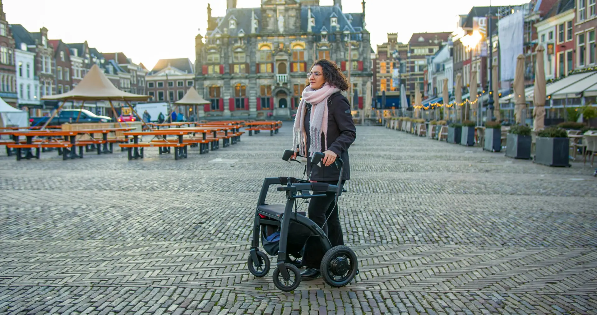 Woman walking with a walker in the historic town square of Delft, Netherlands.
