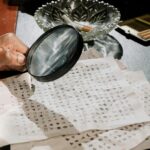 A close-up of a detective analyzing cryptic documents with a magnifying glass.