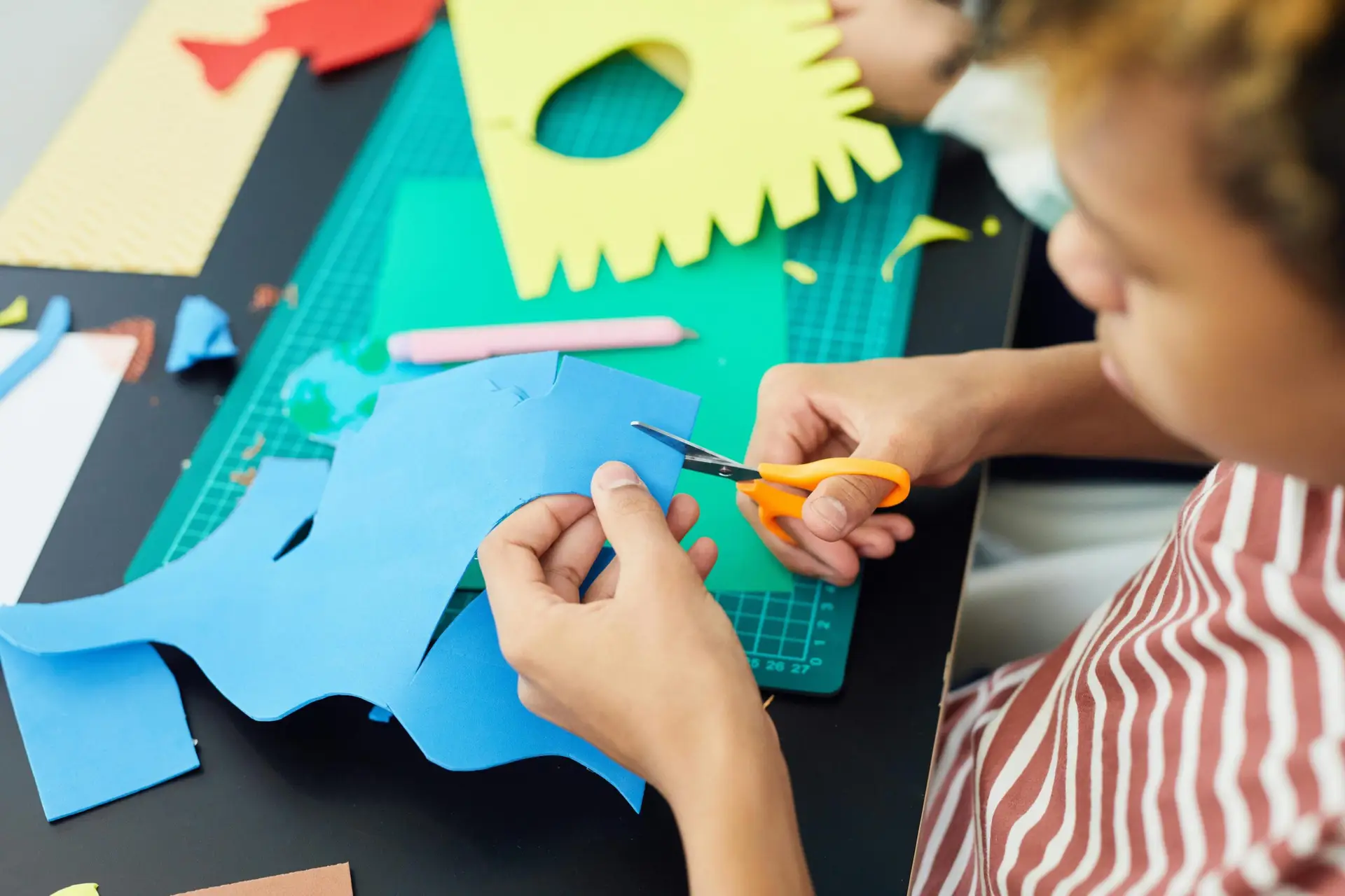 Child cutting colorful paper for arts and crafts activity indoors.