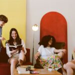 A diverse group of young adults enjoying leisure time reading indoors in a cozy setting.
